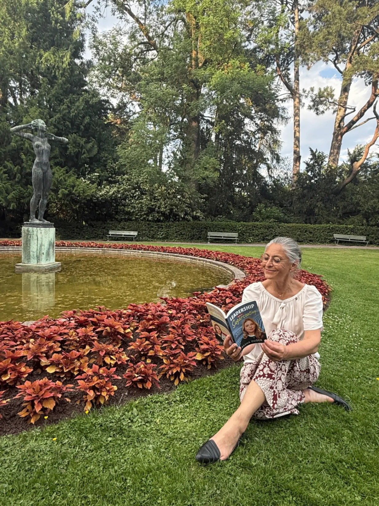 A reader enjoying the book in a garden by a fountain